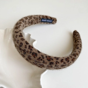 Detail view of leopard print plush headband with handmade label in ceramic tray