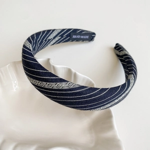 Close-up of handmade navy striped headband with woven texture on a ceramic tray