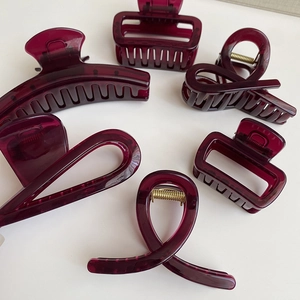 Dettaglio di sei mollette per capelli rosso vino traslucido in varie forme con molle d'oro