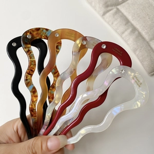 Close-up of wavy U-shaped acetate hairpins in multiple colors with small diamond accents