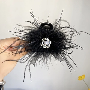 Detail view of black feather hair claw clip featuring a camellia flower decoration