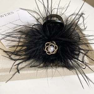 Detail view of feather hair claw with golden camellia flower and pearl decoration
