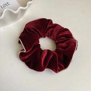 Détail du chouchou en velours bordeaux avec bordure dorée cousue contrastante