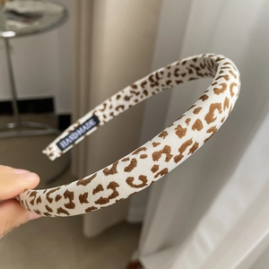 Detail view of the handmade leopard print fabric headband showing the sewn-in brand label