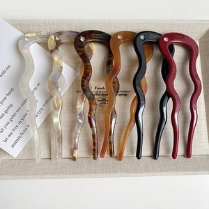Macro detail of wave-shaped acetate U-shaped hair pins in six assorted elegant colors