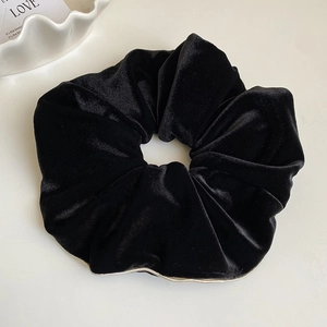 Gros plan sur le chouchou en velours noir avec bordure dorée élégante et texture plissée