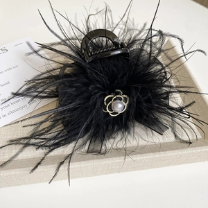 Detail view of large black feather claw clip with camellia flower and pearl decoration