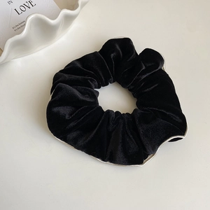 Vue détaillée d'un chouchou en velours noir avec bordure blanche sur fond esthétique blanc