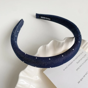 Détail du serre-tête en tissu bleu foncé avec strass argentés et étiquette fait main