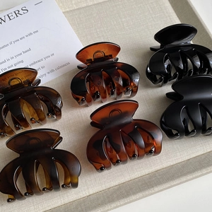 Macro shot of amber and glossy black hair claws on a textured tray showing resin texture