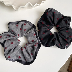 Close-up of heart print scrunchies with satin edges in grey and black fabric