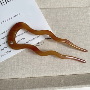 Detailed macro of amber wavy acetate hair pin with crystal inlay and gold handmade text