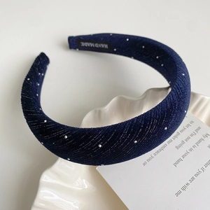 Détail d'un serre-tête en éponge bleu foncé scintillant avec étiquette fait main