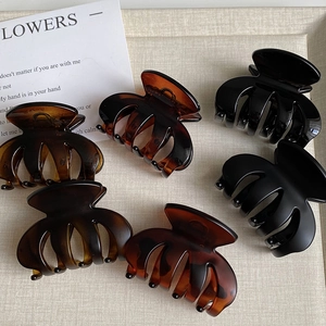 Set of five tortoiseshell and black matte hair claws arranged on a beige textile surface
