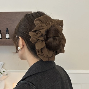 Close-up of a large brown pleated hair scrunchie worn on a ponytail for elegant styling