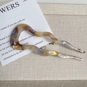 Detail of wave-shaped acetate U-pin with marble texture and inlaid sparkling rhinestone