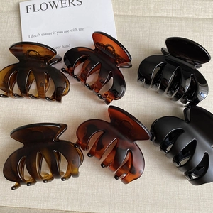 Detailed set of six matte and glossy shark hair claws on a neutral textured background