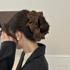 Detailed view of dark brown oversized scrunchie styled in a high bun hair updo