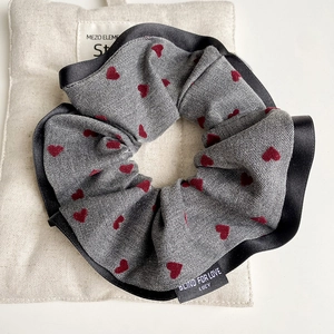 Detail of grey heart-patterned scrunchie fabric texture with satin edge and woven label