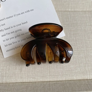 Close-up of amber translucent matte shark clip with a strong metal spring on grey background