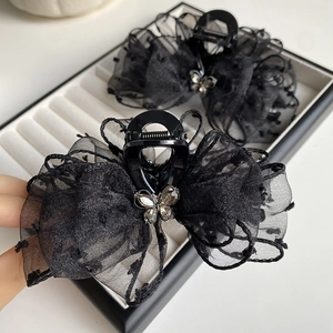 Detailed close-up of a black mesh polka dot bow hair claw clip with a crystal butterfly