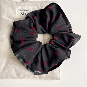 Detail of black scrunchie with red flocked hearts on beige burlap background texture