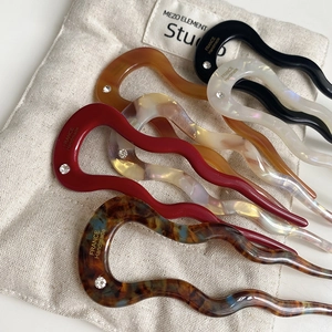 Close-up of wavy acetate hair pins with sparkling rhinestone detail in various colors