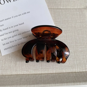 Detail of amber tortoiseshell hair claw clip with glossy finish and metal spring