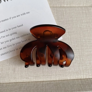 Detailed close-up of dark amber matte hair claw clip with shell pattern texture