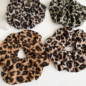 Detail of four leopard print scrunchies in brown, olive, and beige silk-like fabric