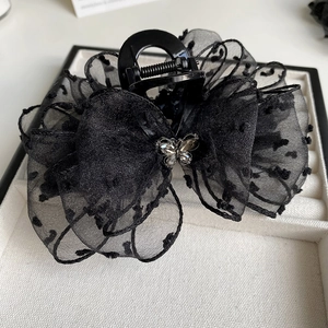 Detailed view of a black mesh bow hair claw clip with polka dots and silver rhinestone butterfly