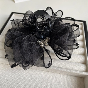 Close-up of a black lace bow hair claw clip with delicate polka dot mesh and butterfly detail
