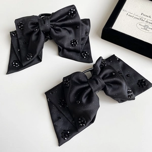 Elegant black satin bow hair clips with crystal flower details on a jewelry box