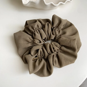 Detail of olive green oversized scrunchie with handmade gold metal tag decoration