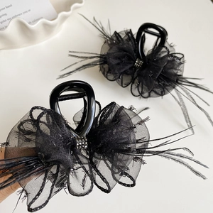 Detail of elegant black feather hair claw with lace flower and sparkling rhinestones