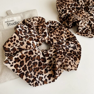 Detail view of two velvet leopard print scrunchies with soft texture and high elasticity