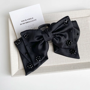 Detail of black satin bow hair claw with sparkling crystal floral accents and fine glitter
