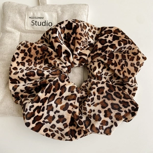 Macro detail of leopard print scrunchie with corduroy texture and elastic band design