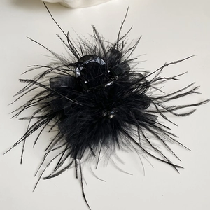 Detail view of a black feather hair claw clip with mesh and sparkling center stone decoration
