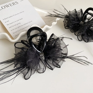 Detail of black feather hair claw clips with mesh bows and sparkling rhinestones