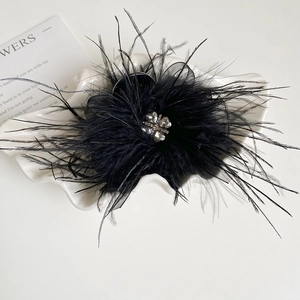 Macro detail of black feather hair claw with clover rhinestone and tulle embellishment