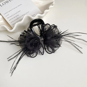 Detail of black hair claw clip featuring mesh bow, feathers, and crystal embellishment