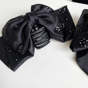 Detail of black satin bow hair claw clip featuring sparkling rhinestone embellishments