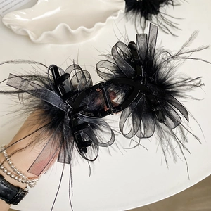 Detailed close-up of a black feather mesh bow claw clip with delicate lace texture