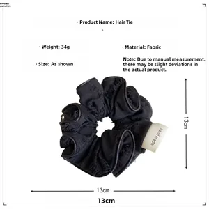 Detail of a vintage black fabric scrunchie with a handmade label and pleated texture