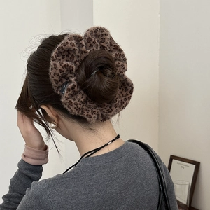 Close-up of a large leopard print plush scrunchie worn on a ponytail for hair styling