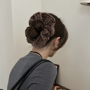 Close-up of fluffy leopard print plush hair scrunchie styled in a high bun hairstyle