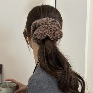 Detailed texture of a plush leopard print hair scrunchie styled on a low ponytail