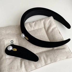 Detail of black velvet headband and clip set with white pearls and gold metal wings tags