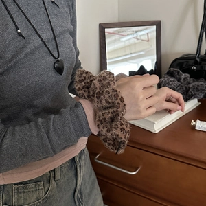 Close-up of leopard print faux fur scrunchie with subtle shimmer on a model's wrist